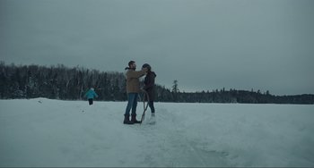 Movie still from “The Lodge” (2019), directed by Severin Fiala – A man and a woman standing in the middle of a snow covered field; Extreme Wide shot, Over the shoulder angle