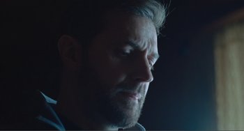 Movie still from “The Lodge” (2019), directed by Severin Fiala – A man's face in the dark; Close Up shot, Low angle