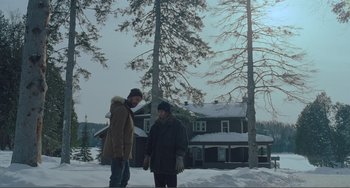 Movie still from “The Lodge” (2019), directed by Severin Fiala – Two people standing in the snow next to a house; Wide shot, Low angle