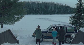 Movie still from “The Lodge” (2019), directed by Severin Fiala – A group of people standing next to an suv in the snow; Extreme Wide shot, High angle