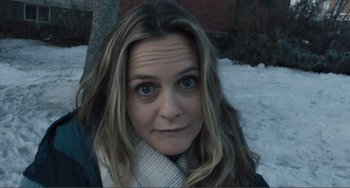 Movie still from “The Lodge” (2019), directed by Severin Fiala – A person wearing a jacket and a scarf; Close Up shot, High angle