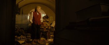Movie still from “The Lord of the Rings: The Fellowship of the Ring” (2001), directed by Peter Jackson – An old man standing in a room with his feet on the floor; Wide shot, Low angle