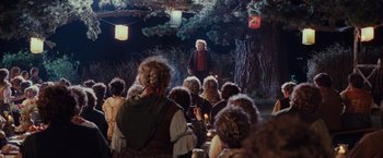 Movie still from “The Lord of the Rings: The Fellowship of the Ring” (2001), directed by Peter Jackson – A group of people sitting in front of a tree; Wide shot, Over the shoulder angle