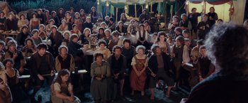 Movie still from “The Lord of the Rings: The Fellowship of the Ring” (2001), directed by Peter Jackson – A large group of people sitting around a table; Wide shot, High angle