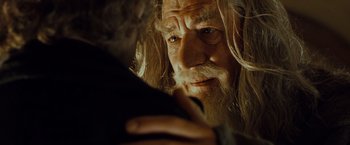 Movie still from “The Lord of the Rings: The Fellowship of the Ring” (2001), directed by Peter Jackson – An old man with long white hair and a beard looking at the camera; Close Up shot, Over the shoulder angle