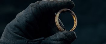 Movie still from “The Lord of the Rings: The Fellowship of the Ring” (2001), directed by Peter Jackson – A gold ring sitting on top of a black glove; Extreme Close Up shot, Overhead angle