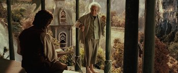 Movie still from “The Lord of the Rings: The Fellowship of the Ring” (2001), directed by Peter Jackson – An old man standing on a balcony with a cane; Wide shot, Over the shoulder angle