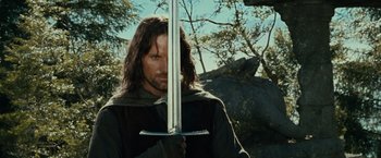 Movie still from “The Lord of the Rings: The Fellowship of the Ring” (2001), directed by Peter Jackson – Aragorn holding a sword up to his face; Medium shot, Low angle