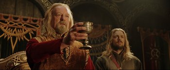 Movie still from “The Lord of the Rings: The Return of the King” (2003), directed by Peter Jackson – A man holding a silver goblet while standing next to another man; Close Up shot, Low angle