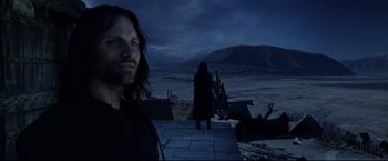Movie still from “The Lord of the Rings: The Return of the King” (2003), directed by Peter Jackson – A man standing on top of a stone walkway; Medium shot, Low angle