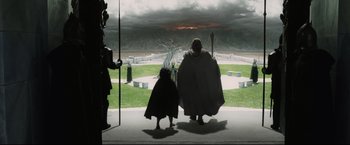 Movie still from “The Lord of the Rings: The Return of the King” (2003), directed by Peter Jackson – A man and a child dressed in costume looking out a window at an event; Wide shot, High angle