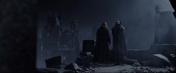 Movie still from “The Lord of the Rings: The Return of the King” (2003), directed by Peter Jackson – Two men in black robes looking out over a city at night; Wide shot, Low angle