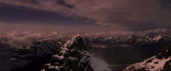 Movie still from “The Lord of the Rings: The Return of the King” (2003), directed by Peter Jackson – A view of a snowy mountain at night with a light shining on it; Extreme Wide shot, High angle