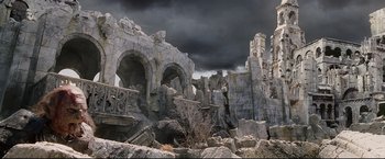 Movie still from “The Lord of the Rings: The Return of the King” (2003), directed by Peter Jackson – A castle like building with a dark sky above it; Extreme Wide shot, Low angle
