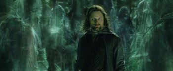 Movie still from “The Lord of the Rings: The Return of the King” (2003), directed by Peter Jackson – A man in a black jacket standing in front of a forest; Medium shot, Low angle