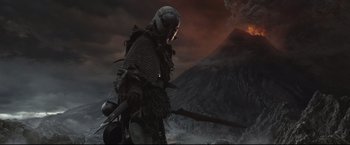 Movie still from “The Lord of the Rings: The Return of the King” (2003), directed by Peter Jackson – A man in a chain mail armor stands in front of an erupting volcano; Wide shot, Low angle