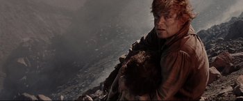 Movie still from “The Lord of the Rings: The Return of the King” (2003), directed by Peter Jackson – A man holding a dog on top of a mountain; Close Up shot, Low angle