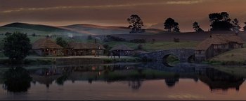 Movie still from “The Lord of the Rings: The Return of the King” (2003), directed by Peter Jackson – A lake with a bridge over it and some houses in the background; Extreme Wide shot, High angle