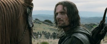 Movie still from “The Lord of the Rings: The Two Towers” (2002), directed by Peter Jackson – A man with long hair standing in the middle of a herd of horses; Close Up shot, Over the shoulder angle