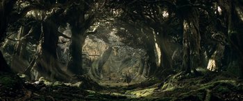 Movie still from “The Lord of the Rings: The Two Towers” (2002), directed by Peter Jackson – A man standing in the middle of a lush forest; Extreme Wide shot, High angle
