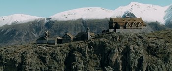 Movie still from “The Lord of the Rings: The Two Towers” (2002), directed by Peter Jackson – An old building on top of a hill with a snowy mountain in the background; Extreme Wide shot, High angle