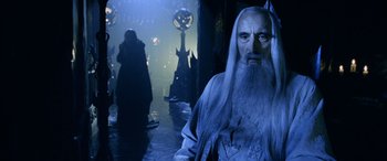 Movie still from “The Lord of the Rings: The Two Towers” (2002), directed by Peter Jackson – A man with a long white beard standing in a room; Medium shot, Over the shoulder angle