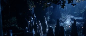 Movie still from “The Lord of the Rings: The Two Towers” (2002), directed by Peter Jackson – A group of people dressed in white standing in the woods; Wide shot, High angle
