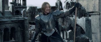 Movie still from “The Lord of the Rings: The Two Towers” (2002), directed by Peter Jackson – A man dressed in armor and holding a sword in his hand; Medium shot, Low angle