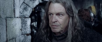 Movie still from “The Lord of the Rings: The Two Towers” (2002), directed by Peter Jackson – An older man with long hair and a black shirt; Close Up shot, Over the shoulder angle