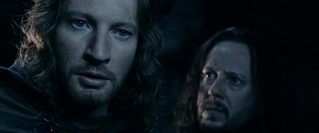 Movie still from “The Lord of the Rings: The Two Towers” (2002), directed by Peter Jackson – A man with long hair is looking at the camera while a man with long hair is looking at the camera; Close Up shot, Over the shoulder angle