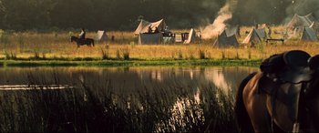 Movie still from “The Magnificent Seven” (2016), directed by Antoine Fuqua – A group of tents sitting next to a body of water; Extreme Wide shot, High angle
