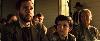 Movie still from “The Magnificent Seven” (2016), directed by Antoine Fuqua – A man and a boy are sitting in front of a window; Close Up shot, Low angle