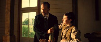 Movie still from “The Magnificent Seven” (2016), directed by Antoine Fuqua – A man and a young boy standing next to each other; Medium shot, Low angle