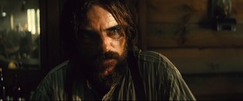 Movie still from “The Magnificent Seven” (2016), directed by Antoine Fuqua – A man with long hair and a goatee stares into the camera; Close Up shot, Low angle