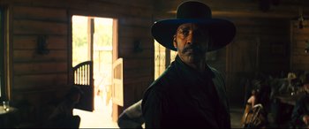 Movie still from “The Magnificent Seven” (2016), directed by Antoine Fuqua – A man with a hat and a beard in front of a door; Medium shot, Low angle