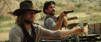 Movie still from “The Magnificent Seven” (2016), directed by Antoine Fuqua – Two men are holding guns while standing next to each other; Medium shot, Over the shoulder angle