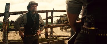 Movie still from “The Magnificent Seven” (2016), directed by Antoine Fuqua – A man in a hat and vest standing in front of a fence; Medium shot, Over the shoulder angle