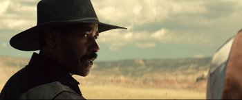 Movie still from “The Magnificent Seven” (2016), directed by Antoine Fuqua – A man in a cowboy hat looking off into the distance; Close Up shot, Over the shoulder angle