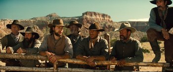 Movie still from “The Magnificent Seven” (2016), directed by Antoine Fuqua – A group of men sitting next to each other on top of a hill; Medium shot, Low angle