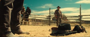 Movie still from “The Magnificent Seven” (2016), directed by Antoine Fuqua – Two men in cowboy hats standing next to a fence; Wide shot, Low angle