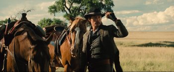 Movie still from “The Magnificent Seven” (2016), directed by Antoine Fuqua – A man standing next to a horse in a field; Medium shot, Low angle