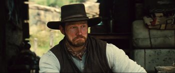 Movie still from “The Magnificent Seven” (2016), directed by Antoine Fuqua – A man with a beard wearing a black hat; Close Up shot, Over the shoulder angle