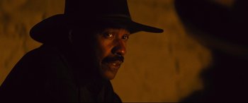 Movie still from “The Magnificent Seven” (2016), directed by Antoine Fuqua – A person wearing a hat; Close Up shot, Over the shoulder angle