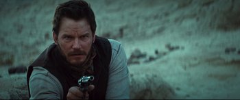 Movie still from “The Magnificent Seven” (2016), directed by Antoine Fuqua – A man holding a gun while standing in the desert; Close Up shot, Over the shoulder angle