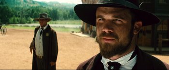 Movie still from “The Magnificent Seven” (2016), directed by Antoine Fuqua – A person wearing a hat and a beard; Close Up shot, Over the shoulder angle