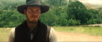 Movie still from “The Magnificent Seven” (2016), directed by Antoine Fuqua – A man wearing a hat and vest in a field; Close Up shot, Over the shoulder angle