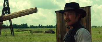 Movie still from “The Magnificent Seven” (2016), directed by Antoine Fuqua – A man wearing a cowboy hat standing in a field; Close Up shot, Over the shoulder angle