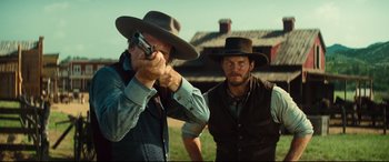 Movie still from “The Magnificent Seven” (2016), directed by Antoine Fuqua – Two men in hats are holding a gun; Medium shot, Low angle