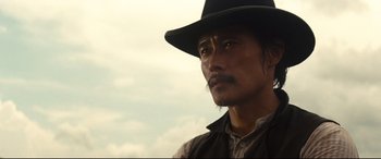 Movie still from “The Magnificent Seven” (2016), directed by Antoine Fuqua – A man in a black hat is looking at the camera; Close Up shot, Low angle