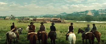 Movie still from “The Magnificent Seven” (2016), directed by Antoine Fuqua – A group of people riding horses in a field; Extreme Wide shot, Low angle